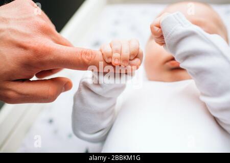 Pieds gros plan d'un nouveau-né. Le petit bébé est allongé sur la table pour enfants . Il y a un enfant de nouveau-né sur la table de changement de bébé près de la fenêtre. Banque D'Images