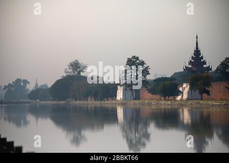 Les murs extérieurs du Palais Mandalay (Mya Nan San Kyaw) et la lune une journée de brume. Scène éthérée avec arbre et bâtiments reflétés dans l'eau Banque D'Images