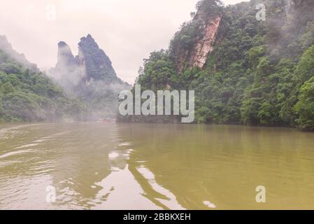 Excursions en bateau sur le lac Baofeng avec forêt luxuriante entourant les hauts sommets de pierre dans la zone panoramique de Wulinguan près de Zhangjiajie, province de Hunan, Chine Banque D'Images