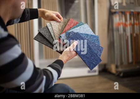 Homme choisissant la couleur rigt de la moquette pour son nouvel appartement en studio de plancher, plancher Banque D'Images