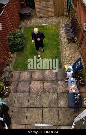 James Campbell, 31 ans, qui est en train de courir un marathon de 26,2 milles dans son jardin à Cheltenham, Gloucestershire tout en étant en verrouillage. Banque D'Images