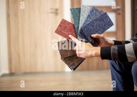 Homme choisissant la couleur rigt de la moquette pour son nouvel appartement en studio de plancher, plancher Banque D'Images