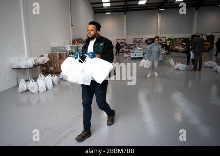 Les bénévoles aident à charger une fourgonnette lors du lancement du centre d'approvisionnement d'Enfield Council à Enfield, dans le nord de Londres. La plate-forme à grande échelle, qui coordonnera les ramasseurs de pharmacie et livrera des aliments et d'autres fournitures aux résidents, est composée de travailleurs du Conseil d'Enfield. Banque D'Images