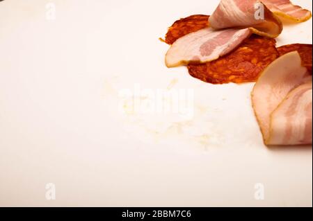 Tranches de bacon et de saucisse sur fond blanc. Gros plan Banque D'Images