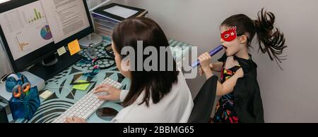 Femme travaillant de la maison avec sa fille chantant de son côté Banque D'Images