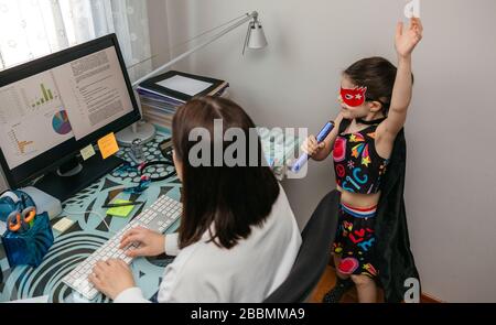 Femme travaillant de la maison avec sa fille chantant de son côté Banque D'Images