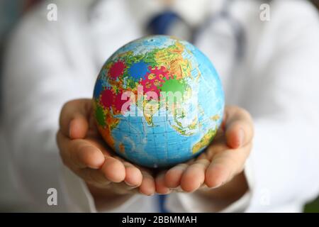 Homme docteur main tenir la terre avec le symbole de virus closeup. Banque D'Images