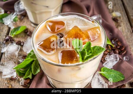 Café d'été froid, latte, frappe, frappuccino. Cocktail glacé au café avec glaçons, lait ou lait non laitier congelés et feuilles de menthe. Woode Banque D'Images