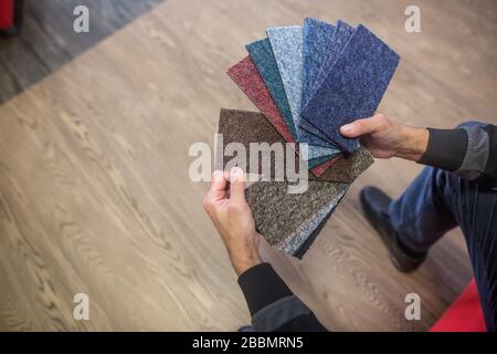 Homme choisissant la couleur rigt de la moquette pour son nouvel appartement en studio de plancher, plancher Banque D'Images