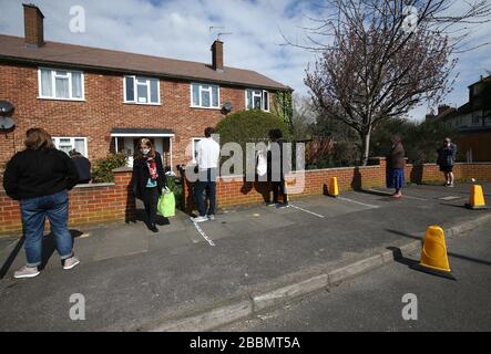 Les habitants de la région s'alignent pour collecter des paquets de nourriture du jardin avant de la maison de James Giles à New Malden, au sud-ouest de Londres. Les denrées périssables, qui ne sont pas acceptées par les banques alimentaires en raison des dates d'expiration courtes, sont données au Kingston upon Thames charité Save the World Club par les supermarchés locaux et sont distribuées gratuitement à la communauté locale depuis le jardin avant de la maison de James Giles à New Malden. Depuis le déclenchement du coronavirus, la nourriture est annoncée en ligne dans les groupes communautaires Facebook et quiconque en a besoin peut se recueillir du jardin avant de la maison de M. Giles chaque matin, où il opère Banque D'Images