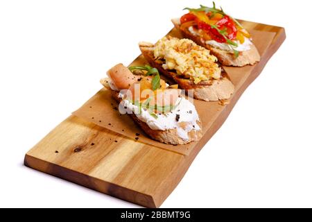 Bruschetta avec saumon sur un panneau de bois sur fond blanc. Pain grillé avec avocat et poisson rouge. Le concept est utile et délicieux petit déjeuner Banque D'Images