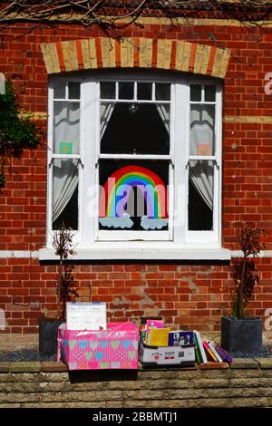 1 avril 2020, Southborough, Kent, Royaume-Uni: Libre échange de livres / bibliothèque de prêt sur le mur avant à l'extérieur de la maison pendant le gouvernement a imposé la quarantaine / le verrouillage pour réduire la propagation du coronavirus. Les enfants de tout le pays ont mis des dessins d'arcs-en-ciel dans des fenêtres pour répandre l'espoir et encourager les gens à rester enjoués pendant la pandémie. Ils ont aussi eu des idées pour empêcher les autres de s'ennuyer, dans ce cas encourageant la lecture et fournissant des moyens de se tenir des différents livres à lire Banque D'Images