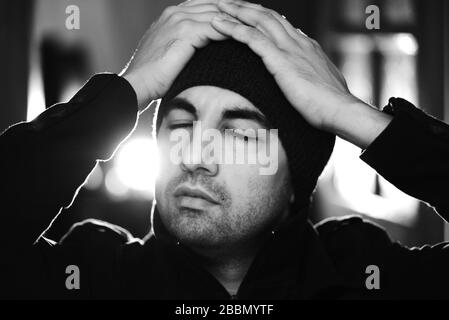 Photo en noir et blanc de l'homme d'âge moyen montrant de graves émotions. Beardy mâle dans un manteau noir et chapeau avec un look sérieux. Banque D'Images