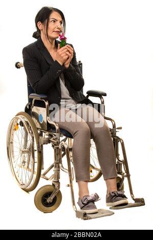 Femme en fauteuil roulant qui sent une fleur isolée sur fond blanc Banque D'Images