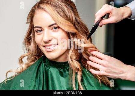 Les mains de coiffeur peignes cheveux de femme souriante dans le salon de coiffure. Banque D'Images