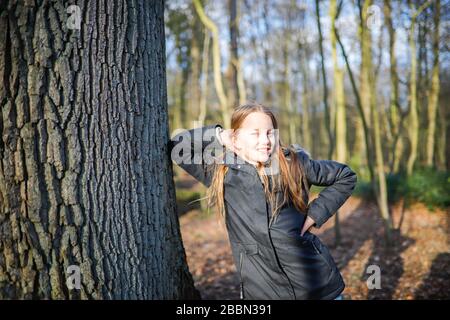 Une fille de 11 ans se penche sur le tronc d'un arbre énorme Banque D'Images