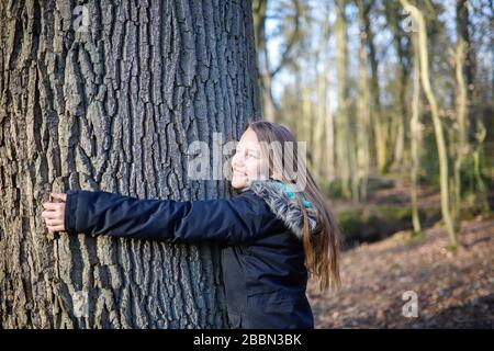 Une fille de 11 ans embrasse le tronc d'un arbre énorme Banque D'Images