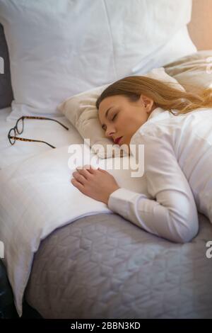 Une femme d'affaires fatiguée dore dans la chambre de l'hôtel. Banque D'Images