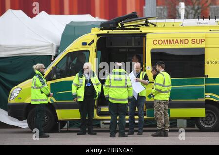 Les équipes d'ambulance et le personnel militaire attendent les premiers patients du centre Excel de Londres qui est en train d'être rendus à l'hôpital temporaire NHS Nightingale pour aider à lutter contre le coronavirus. Banque D'Images