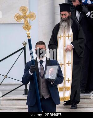 Athènes, Grèce. 1 er avril 2020. Un porteur de cercueil, portant des masques et des gants de protection noirs, est titulaire d'une photographie du héros et politicien de la résistance de la guerre du ver grec Manolis Glezos, lors de ses funérailles auxquelles ont assisté uniquement des membres de sa famille, par mesure de précaution contre la propagation de la pandémie de coronavirus de Covid-19, à Athènes, en Grèce. Manolis Glezos le 30 mai 1941, à l'âge de 18 ans, a grimpé avec Apostolos Santas sur l'Acropole et a torqué le drapeau de la swastika, trois jours après que les forces nazies ont occupé Athènes et sont devenues un symbole de la résistance anti-nazie grecque et internationale. Le politicien de gauche grec, qui Banque D'Images