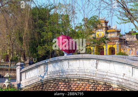 Dame vietnamienne avec parasol marchant sur un pont dans la Citadelle impériale, près de la porte principale Truong an mon , Hue, Vietnam, Asie du Sud-est Banque D'Images