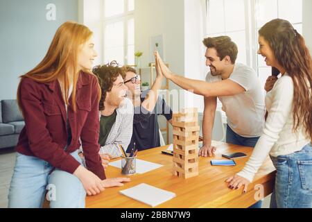 Un groupe de jeunes jouent à des jeux de société donnent cinq sièges à une table dans la chambre. Banque D'Images