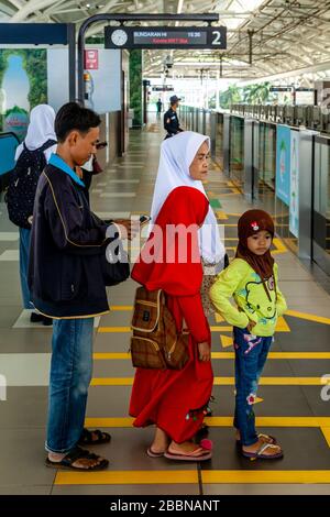 Une famille indonésienne attend sur la plate-forme de la gare comme un train approche, le métro (MRT), Jakarta, Indonésie. Banque D'Images