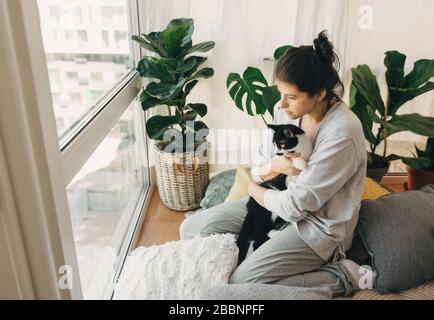 Triste fille embrassant chat mignon, assis ensemble à la maison pendant la quarantaine de coronavirus. Restez à la maison en sécurité. Isolement à domicile pour prévenir l'épidémie de virus. Y Banque D'Images