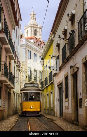 Rue étroite dans le vieux centre-ville de Lisbonne avec un tramway électrique jaune typique Banque D'Images