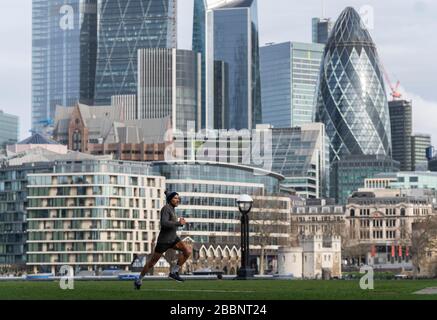 © 2020 Andrew Baker. LONDRES ROYAUME-UNI. 20 mars 2020 UN joggeur traverse un Potter Fields Park vide dans un contexte de la ville de Londres. Après le Banque D'Images