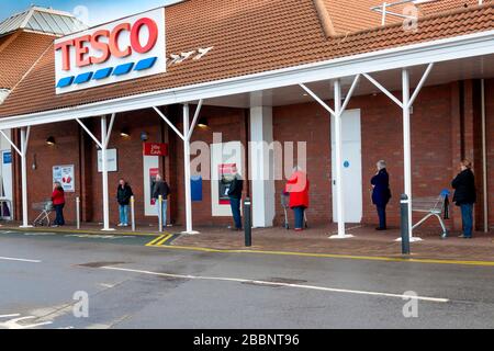 Une file d'attente de personnes qui attendent d'entrer dans un supermarché Tesco, elles sont espacées de 2 mètres en tant qu'espacement sûr pendant la pandémie de coronavirus ou de Covi9 19 Banque D'Images