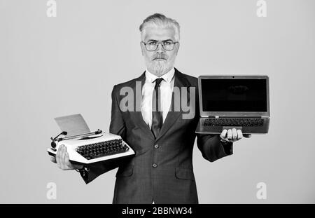 Apprenez-en plus facilement. Bon homme d'affaires utilise une machine à écrire rétro et un ordinateur portable moderne. Cheveux de barbe teints par l'homme. Ordinateur ou machine à écrire. Nouvelles et anciennes technologies. Entreprise numérique moderne. Machine à écrire vintage. Banque D'Images