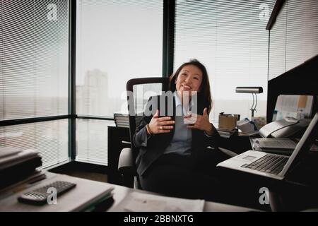 Femme qui parle et siège au bureau. Banque D'Images