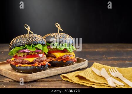 Deux hamburgers noirs sur fond en bois sombre Banque D'Images