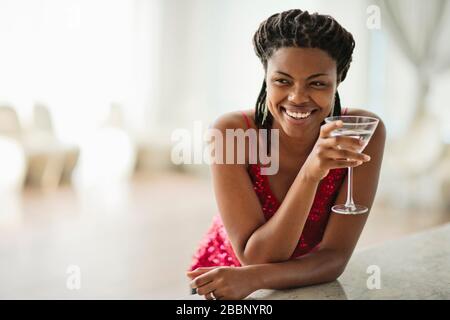 Souriante jeune femme dégustant un cocktail dans un bar. Banque D'Images