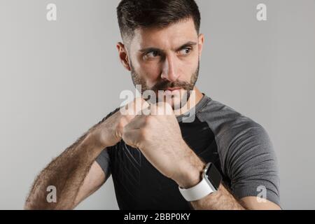 Image d'un chasseur sportif puissant isolé sur fond de mur gris debout dans la posture de boxe. Banque D'Images