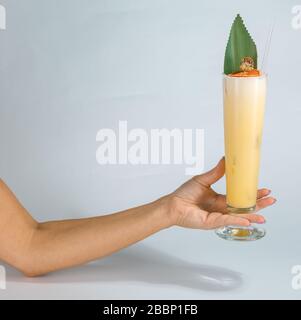 Gros plan sur la main d'une femme tenant un verre de cocktail tropical Pina colada sur fond blanc avec espace de copie. Concept de vacances d'été. Banque D'Images