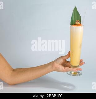 Gros plan sur la main d'une femme tenant un verre de cocktail tropical Pina colada sur fond blanc avec espace de copie. Concept de vacances d'été. Banque D'Images