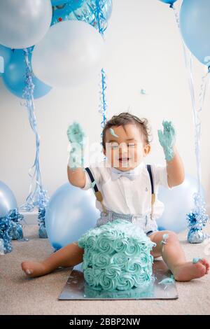 Bébé garçon en noeud papillon et bretelles à la fête de gâteau de 1er anniversaire Banque D'Images