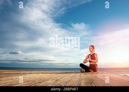 femme pratiquant la méditation matinale dans la nature par la mer, concept de mode de vie sain. Banque D'Images