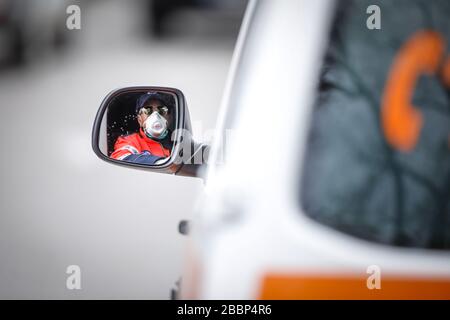 Bucarest, Roumanie - 1er avril 2020 : conducteur d'ambulance vu dans le rétroviseur latéral du véhicule. Banque D'Images