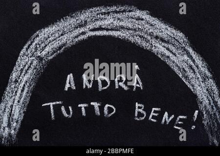 Dessiner avec de la craie sur un tableau noir, le texte italien manuscrit andrá tutto bène qui se traduit comme tout va bien Banque D'Images