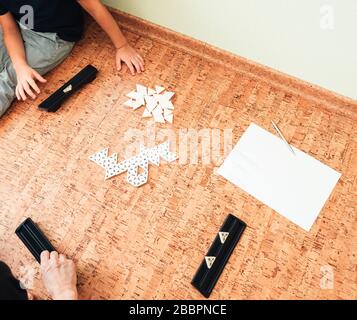 La famille joue le sol dans un jeu de table de trimino. Vue de dessus. Développement du jeu Banque D'Images