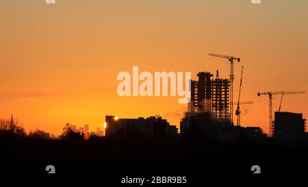 Le soleil se cachant de chaque côté du coin d'un bâtiment, car il s'élève au-dessus de l'horizon urbain de West London, au Royaume-Uni Banque D'Images