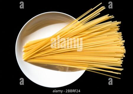 Pâtes italiennes brutes originales sur une plaque blanche. Linguine prête à être cuite. Concept d'ingrédient de cuisine italienne. Banque D'Images