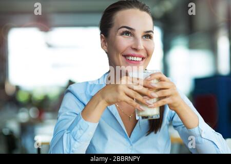 Femme buvant du latte macchiato au café Banque D'Images