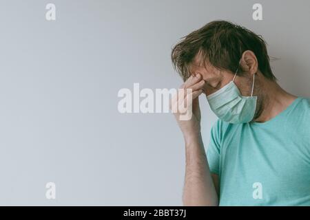 Homme avec masque ayant des maux de tête de migraine comme symptômes de Covid-19, portrait de homme avec infection virale pendant les pandémies Banque D'Images