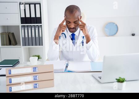 Photo de la famille doc sombre peau professionnel gars écrire des prescriptions patients base journal doigts sur les temples travail jour nuit fatigué porter blanc manteau de laboratoire Banque D'Images