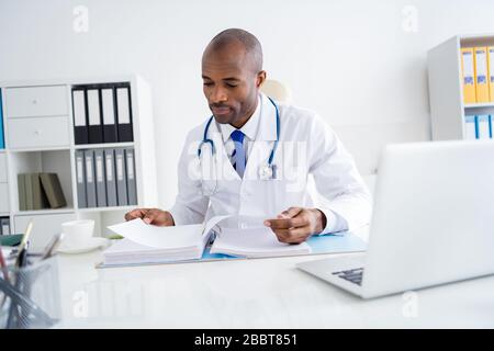 Photo de la famille doc peau sombre gars professionnel réussi écrire liste des prescriptions de contrôle de grands patients base journal activités porter blanc blouse de laboratoire Banque D'Images