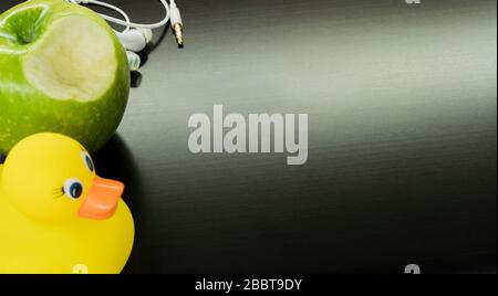 casque blanc, canard jaune et pomme verte sur un ordinateur noir Banque D'Images